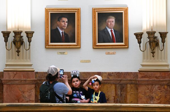 Туристка фотографирует детей под портретами бывшего президента США Барака Обамы и президента США Дональда Трампа в ротонде Капитолия штата Колорадо в Денвере. - Sputnik Казахстан