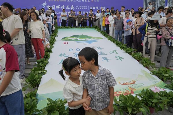 Мальчик целует девочку во время Праздника лодок-драконов, проходящего вдоль северной части Большого канала в Тунчжоу, пригороде Пекина, Китай. - Sputnik Казахстан