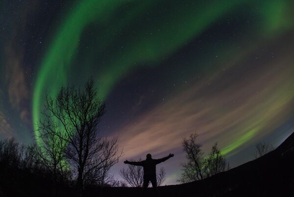 Турист позирует перед фотокамерой на фоне полярного сияния в окрестностях города Мурманск. Многие хотели бы иметь в личной коллекции такой потрясающий кадр! - Sputnik Казахстан