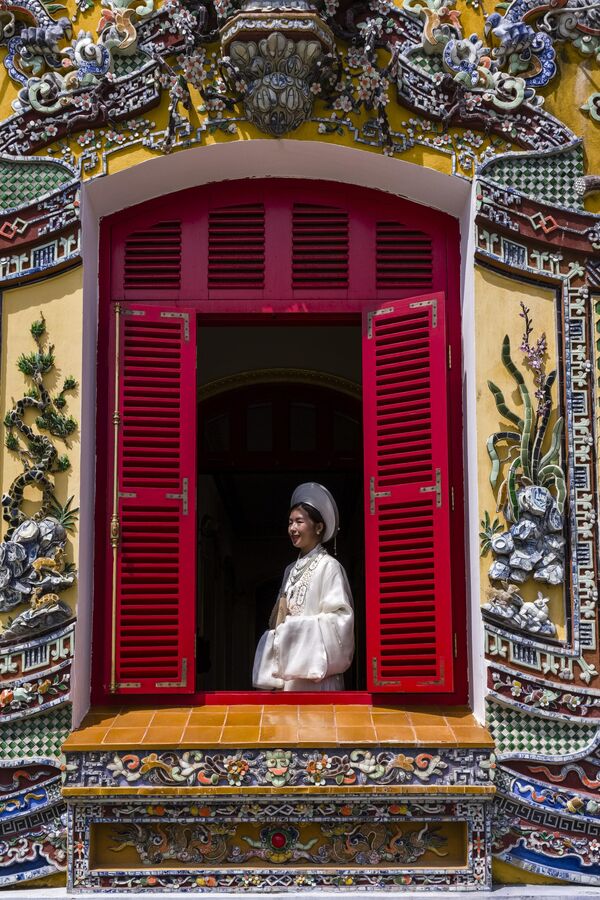 Женщина в национальной одежде фотографируется во дворце Киенчунг в Кинчунге, Вьетнам. Этот прекрасный дворец после почти 70-летнего пребывания в руинах вновь открыт для туристов. - Sputnik Казахстан