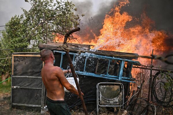 Мужчина тушит пожар в поселке Ольховские дачи Станично-Луганского округа Луганской народной республики - Sputnik Казахстан