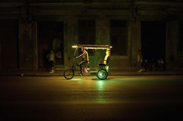 Мужчина управляет рикшей во время затемнения в Гаване, Куба. - Sputnik Казахстан