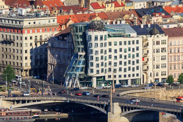 Танцующий дом в Праге в Чехии. Это необычное офисное здание построили архитекторы Владо Милунич и Фрэнк Гери в 1996 году. В шутку это архитектурное сооружение называют "Джинджер и Фред", в честь знаменитой танцующей пары из одноименного фильма. Та часть здания, что расширяется кверху, олицетворяет Фреда, а сторона с "тонкой талией" и развивающейся книзу "юбкой" — это Джинджер. - Sputnik Казахстан