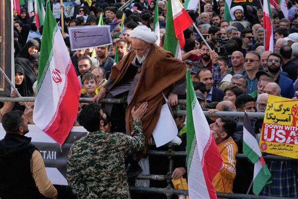 Священнослужитель пытается преодолеть ограждение во время ежегодного митинга перед бывшим посольством США в Тегеране, посвященного годовщине захвата посольства в 1979 году, Иран. - Sputnik Казахстан