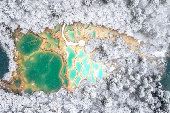 Қытайдың Сычуань провинциясындағы Цзючжайгоу ұлттық саябағындағы түрлі-түсті әктас бассейндердің (көбінесе пері бассейндері деп аталады) көрінісі. Жұқа қар жамылғысының астында бассейндердің түбіндегі көк-жасыл түсті өрнектер айдаһардың қабыршағына ұқсап жарқырайды. - Sputnik Қазақстан