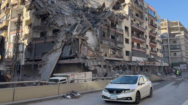 Автомобиль проезжает перед разрушенным зданием, пострадавшим от израильского авиаудара в Дахие, южном пригороде Бейрута, Ливан - Sputnik Казахстан