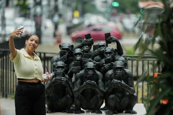 Женщина делает селфи рядом со скульптурой бразильского художника Бето Гатти под названием "Разъединенные" на тротуаре в рамках выставки "Primordios Digitais" в Сан-Паулу, Бразилия. - Sputnik Казахстан