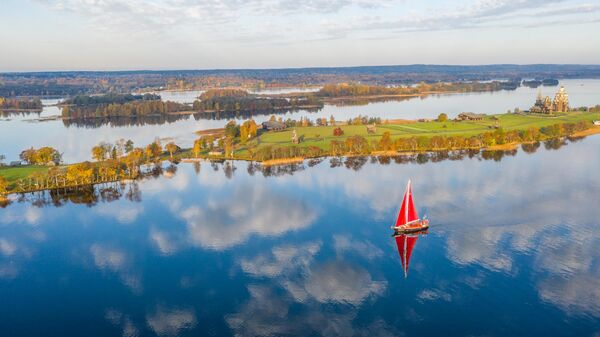 Экспедиционная яхта "Петр Первый" рядом с островом Кижи, где видны Преображенская церковь XVIII века, церковь Покрова Пресвятой Богородицы и колокольня, входящие в состав архитектурного ансамбля одноименного заповеднка. - Sputnik Казахстан
