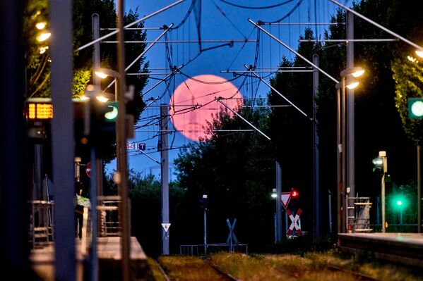 Кроме того, это астрономическое явление связано с тем, что спутник Земли поднимается над горизонтом на минимальное расстояние, вследствие чего Луна будет выглядеть алой, напоминая цвет поспевающей клубники. На фото: луна над станцией метро во Франкфурте, Германия. - Sputnik Казахстан