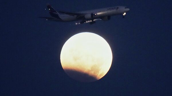 Самолет Boeing 777 авиакомпании LATAM Airlines приближается к посадке в Лиссабоне во время частичного лунного затмения, пятница, 28 августа 2026 года.  - Sputnik Казахстан