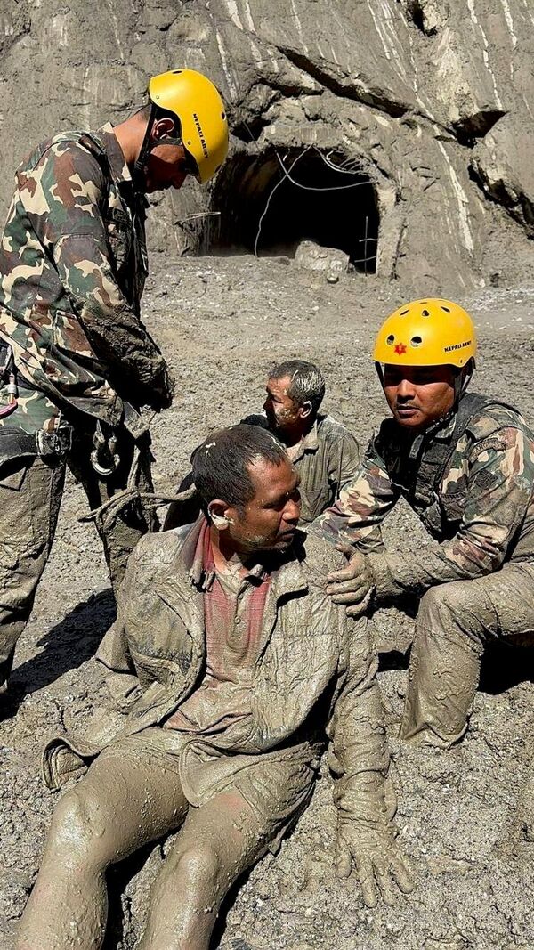 Женщина помогает мальчику прикрепить фото пропавшего родственника к стене с портретами пропавших и погибших возле больницы в Катманду, Непал. - Sputnik Казахстан