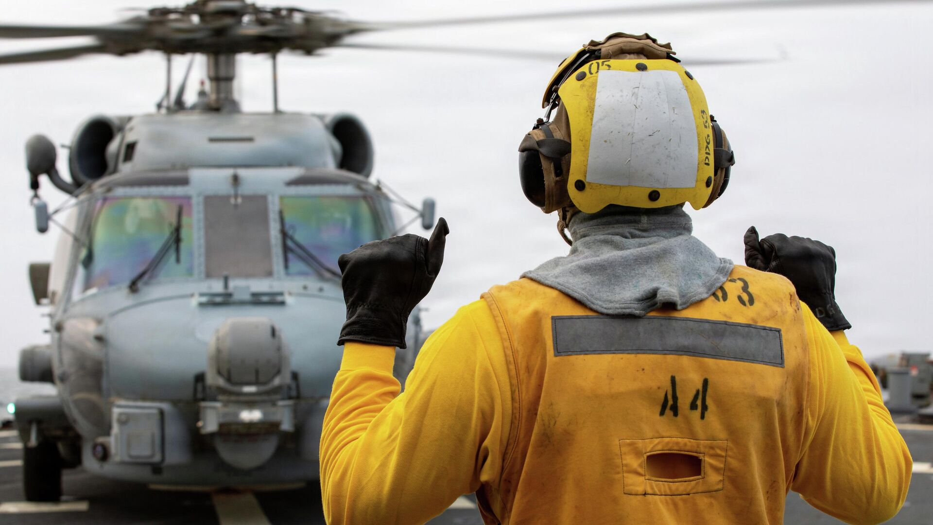 Американский моряк подает сигналы пилоту вертолета MH-60R Sea Hawk на летной палубе эсминца - Sputnik Казахстан, 1920, 14.09.2026