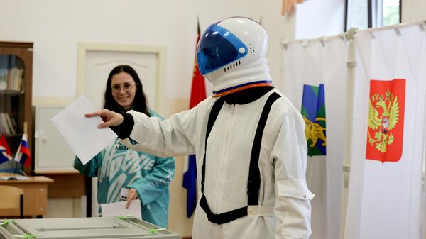 Избиратель в костюме космонавта опускает бюллетень в урну на парламентских выборах во Владивостоке, Россия - Sputnik Казахстан