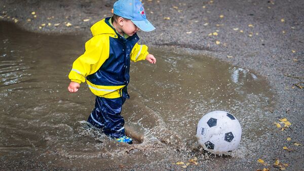 Ребенок играет в мяч после дождя. - Sputnik Казахстан