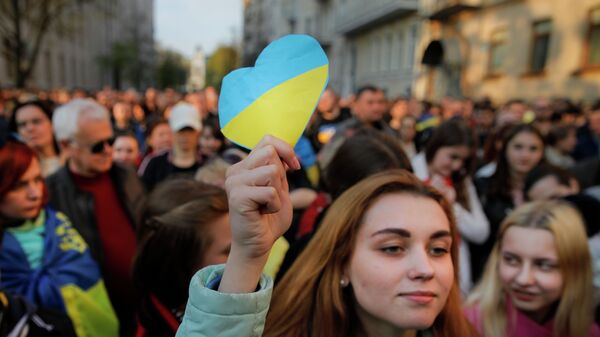 Девушка держит бумажное сердце в цветах украинского флага - Sputnik Казахстан