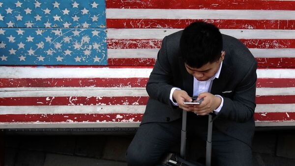 Мужчина сидит на скамейке, раскрашенной в цветах американского флага - Sputnik Казахстан