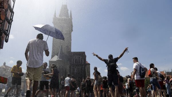 Люди охлаждаются под струей воды в жаркий и летний день на Староместской площади в Праге, Чехия - Sputnik Казахстан