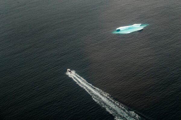 Катер проходит мимо айсберга в открытом океане возле Тасиилака, Гренландия - Sputnik Казахстан