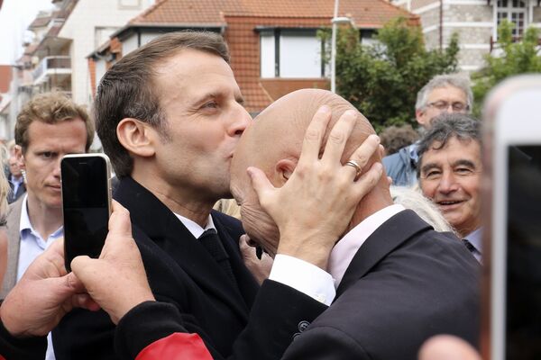 Президент Франции Эммануэль Макрон целует сторонника после голосования на выборы в европарламент в Ле-Туке на севере Франции - Sputnik Казахстан