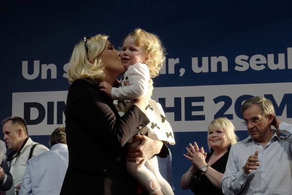 Марин ле Пен целует девочку во время предвыборного митинга в Энен-Бомоне, Франция - Sputnik Казахстан