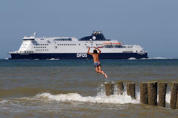 Мальчик прыгает в море в жаркий летний день на пляже в Сангатте, Франция - Sputnik Казахстан