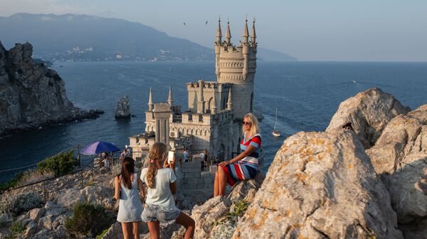 Отдыхающие фотографируются возле замка Ласточкино гнездо на береговой скале в поселке Гаспра в Крыму - Sputnik Қазақстан