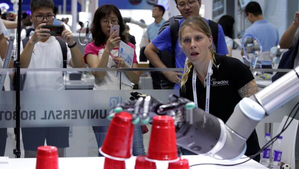 Инженер расставляет пластиковые стаканы при помощи системы дистанционного управления на стенде Universal Robots на Всемирной конференции роботов (WRC) в Пекине, Китай. - Sputnik Казахстан