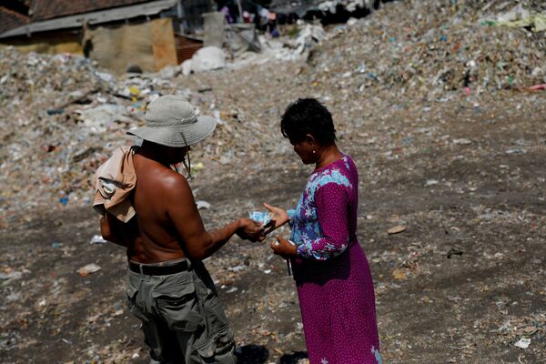 Местная жительница получает деньги после выгрузки мусора в ее родной деревне Бангун, Индонезия - Sputnik Казахстан