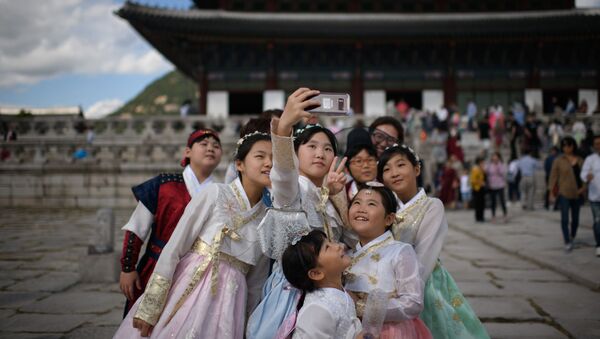 Одетые в традиционные корейские платья посетители фотографируются перед павильоном во дворце Кёнбоккун в Сеуле, архивное фото - Sputnik Казахстан