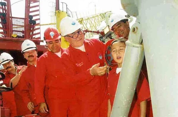 На церемонии официального открытия проекта на месторождении Кашаган президент Нурсултан Назарбаев мажет первой нефтью семилетнему Берику лицо  - Sputnik Казахстан