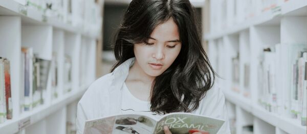 Девушка читает книгу в библиотеке - Sputnik Казахстан