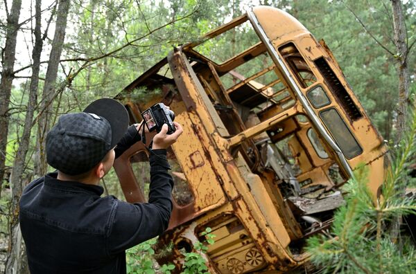 Турист фотографирует автобус в зоне отчуждения Чернобыльской АЭС - Sputnik Казахстан
