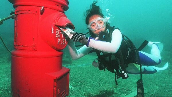 Водолаз кладет пластиковое письмо в почтовый ящик, установленный на глубине 10 метров на дне моря у берегов Сузами в префектуре Вакаяма - Sputnik Казахстан