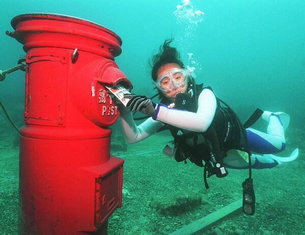 Водолаз кладет пластиковое письмо в почтовый ящик, установленный на глубине 10 метров на дне моря у берегов Сузами в префектуре Вакаяма - Sputnik Казахстан