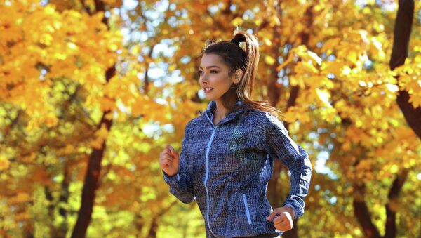 Девушка в осенней спортивной куртке занимается бегом в парке - Sputnik Казахстан
