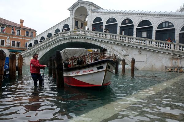 Человек привязывает лодку к мосту во время наводнения в Венеции - Sputnik Казахстан