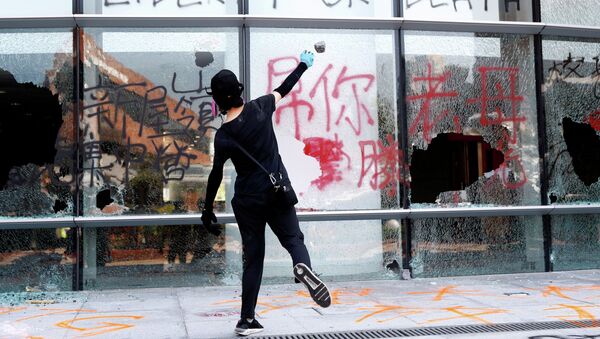  Протестующий бросает камень в здание политехнического университета в Гонконге, Китай - Sputnik Казахстан