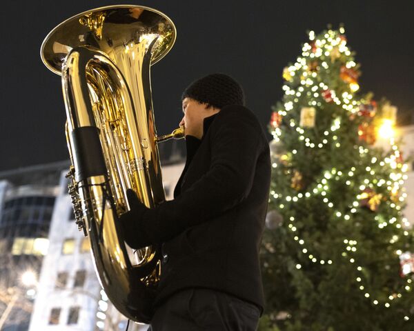 Музыкант духового оркестра Rudersdorf Music Society играет на трубе на рождественском базаре в Вене - Sputnik Казахстан