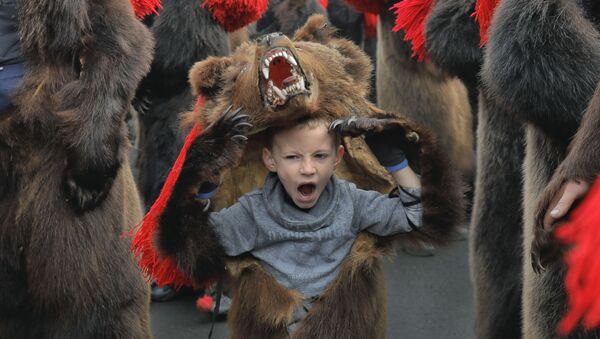Зевающий мальчик в костюме медведя на новогоднем шествии в румынском городе Комэнешти - Sputnik Казахстан