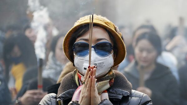 Женщина в маске и солнцезащитных очках во время молитвы в первый день Нового года в Пекине - Sputnik Қазақстан