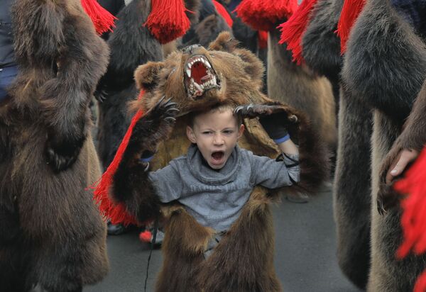 Зевающий мальчик в костюме медведя на новогоднем шествии в румынском городе Комэнешти - Sputnik Казахстан