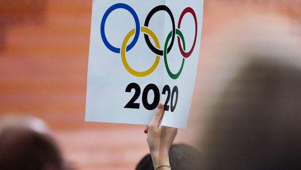 Журналист держит плакат с олимпийскими кольцами - Sputnik Казахстан