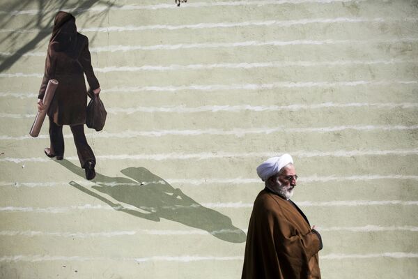 Иранский священнослужитель проходит мимо фрески с изображением женщины в центре Тегерана - Sputnik Казахстан