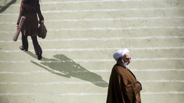 Иранский священнослужитель проходит мимо фрески с изображением женщины в центре Тегерана - Sputnik Казахстан