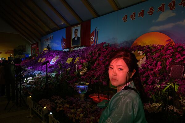 Посетительница под портретом Ким Ир Сена на цветочной выставке в рамках празднования Дня солнца в Пхеньяне - Sputnik Казахстан