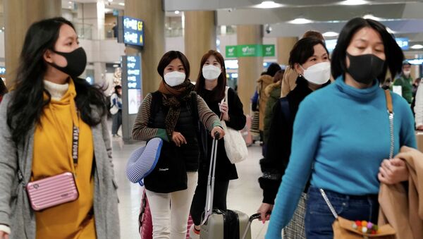Люди в защитных масках для предотвращения заражения коронавирусом покидают аэропорт - Sputnik Казахстан
