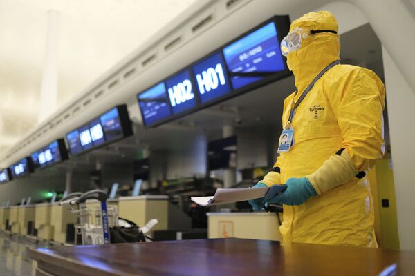 Работник в защитном костюме в аэропорту Уханя - Sputnik Казахстан