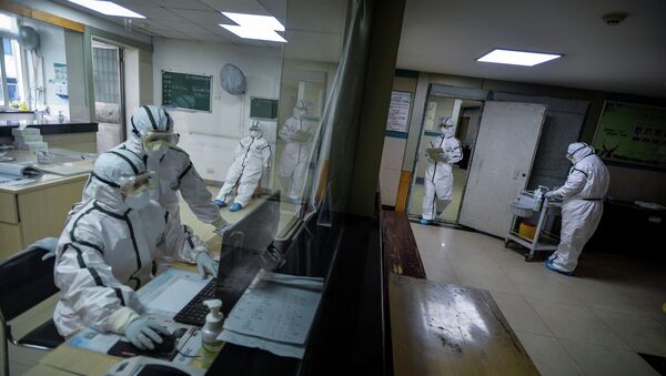 Медицинские работники в защитных костюмах работают в изолированном помещении общественного центра здравоохранения в Ухани - Sputnik Казахстан