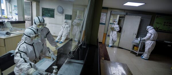 Медицинские работники в защитных костюмах работают в изолированном помещении общественного центра здравоохранения в Ухани - Sputnik Казахстан