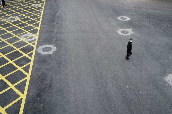 Человек в защитной маске пересекает опустевшую улицу в Ухане - Sputnik Казахстан
